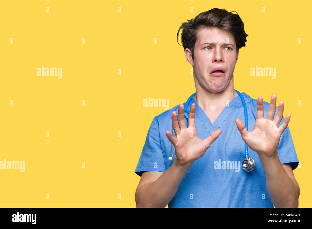 Young doctor wearing medical uniform over isolated background afraid ...