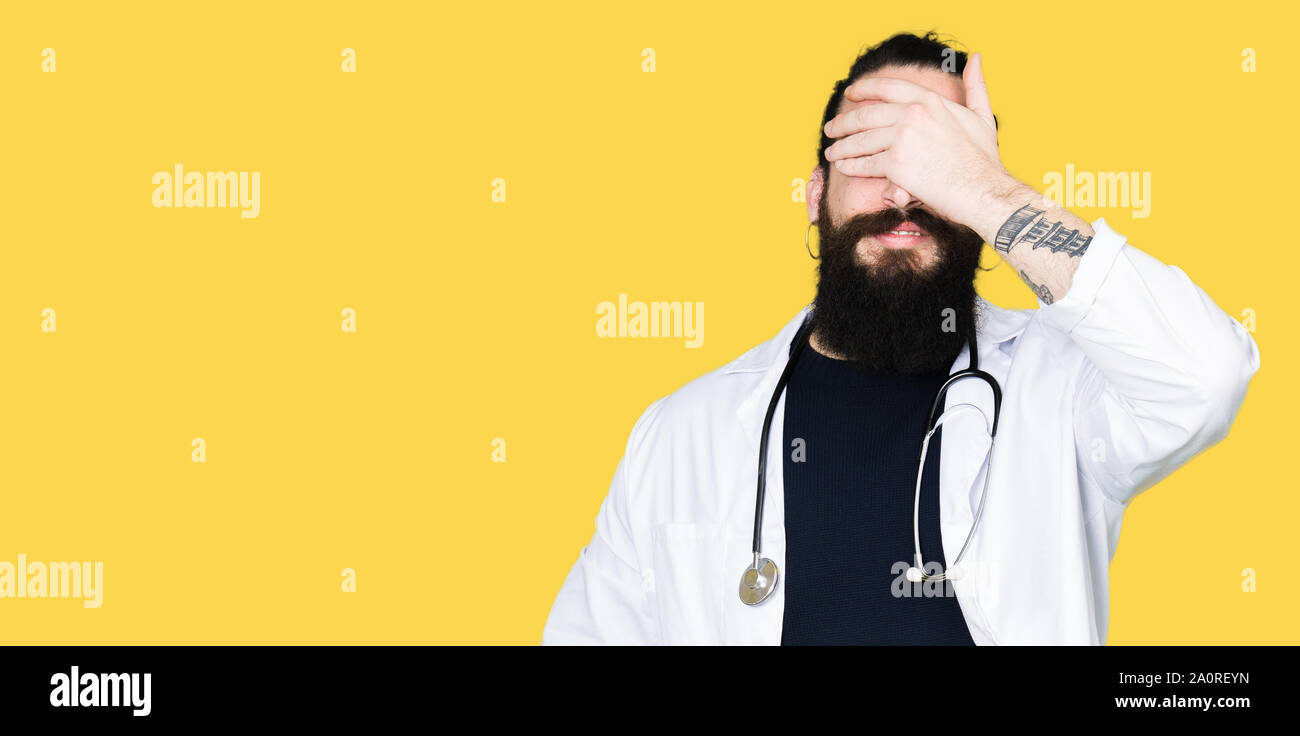 Smiling Reyn Doctor with long hair wearing medical coat and stethoscope smiling and ...