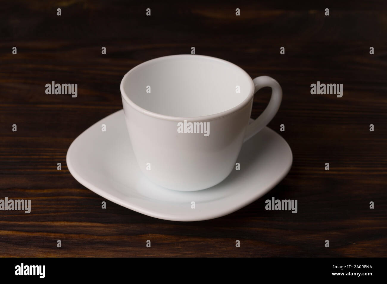 Empty white teacup and saucer on old wood texture background. Empty teacup and saucer set on wood plank table surface Stock Photo