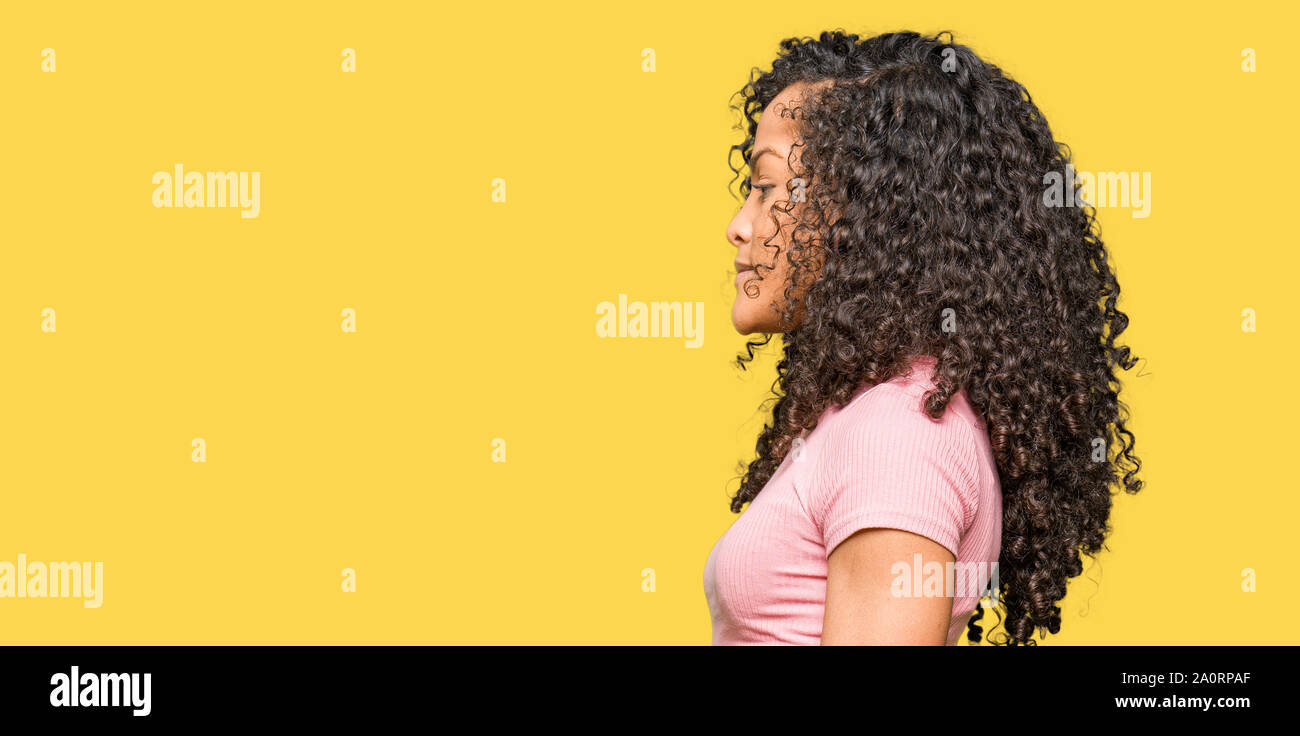 Young Beautiful Woman With Curly Hair Wearing Pink T Shirt Looking