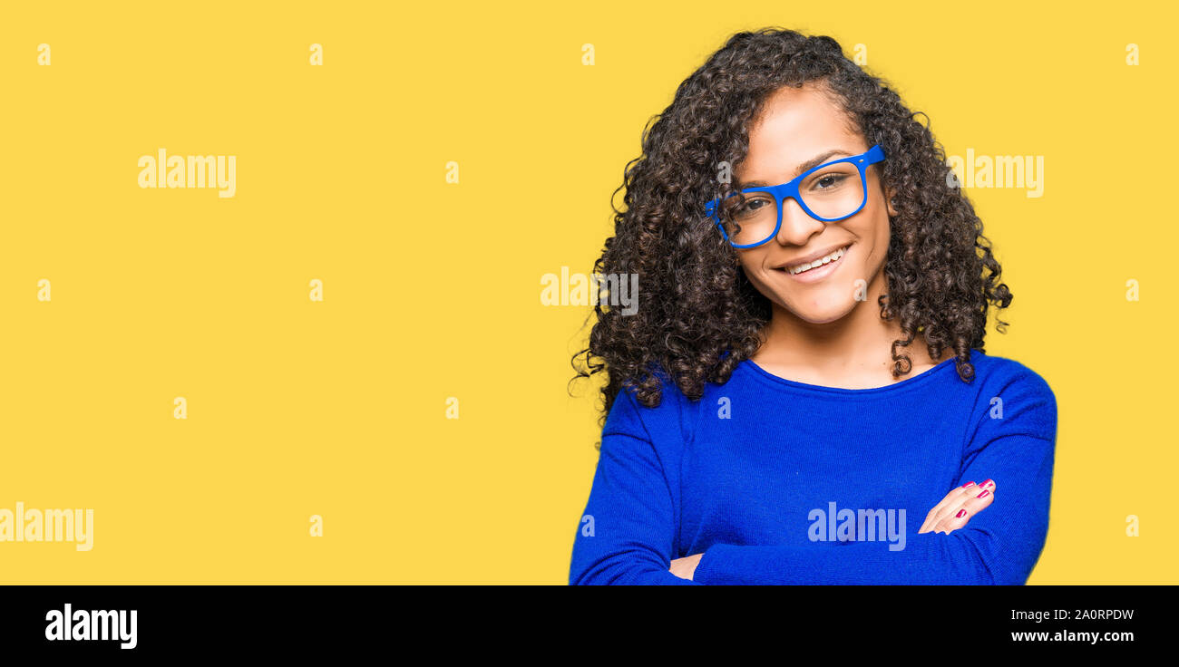 Young beautiful woman with curly hair wearing glasses happy face ...