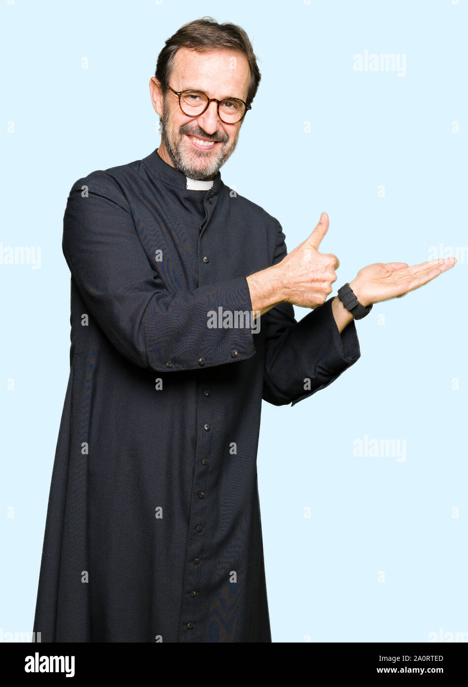 Middle age priest man wearing catholic robe Showing palm hand and doing ...