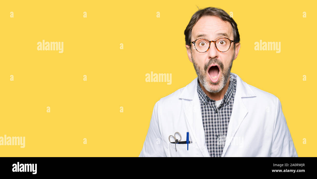 Middle age doctor men wearing medical coat afraid and shocked with ...
