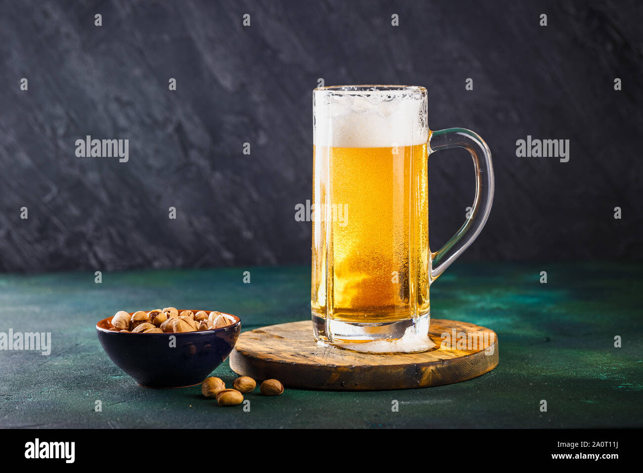 Glass mug with beer with foam and water drops and snacks on a dark green background Stock Photo