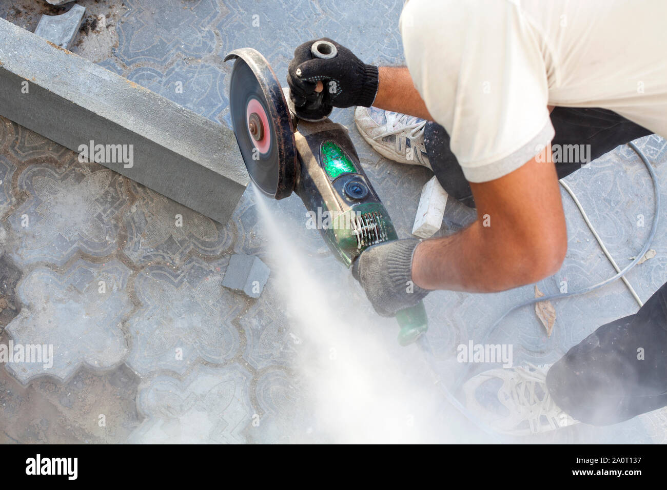 A worker at the construction site saws off a piece of concrete curb