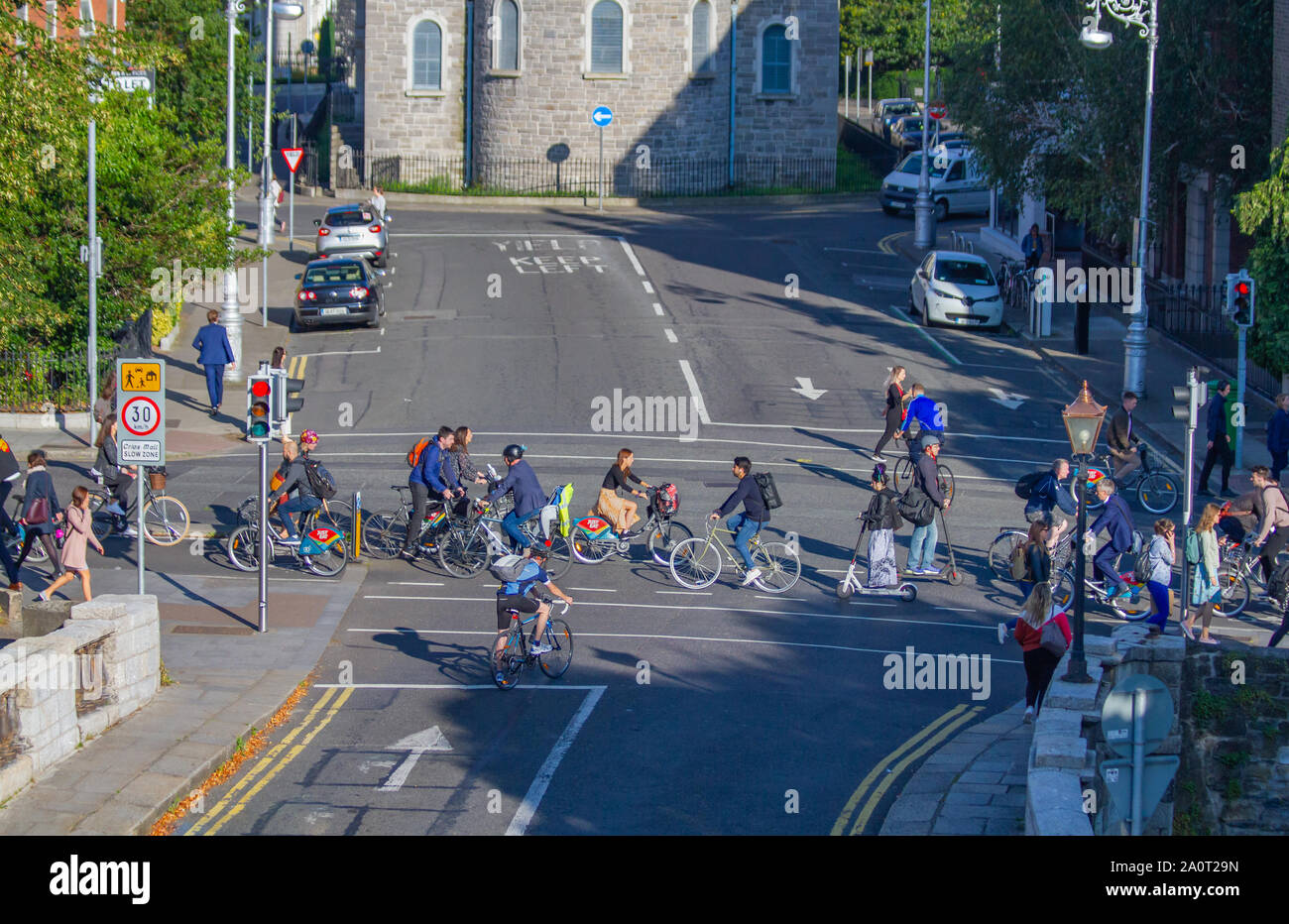 Morning commuters ride to work on bicycles and e scooters in dedicated bicycle lane. Dublin, Ireland green lifestyle. Electric car charging Stock Photo