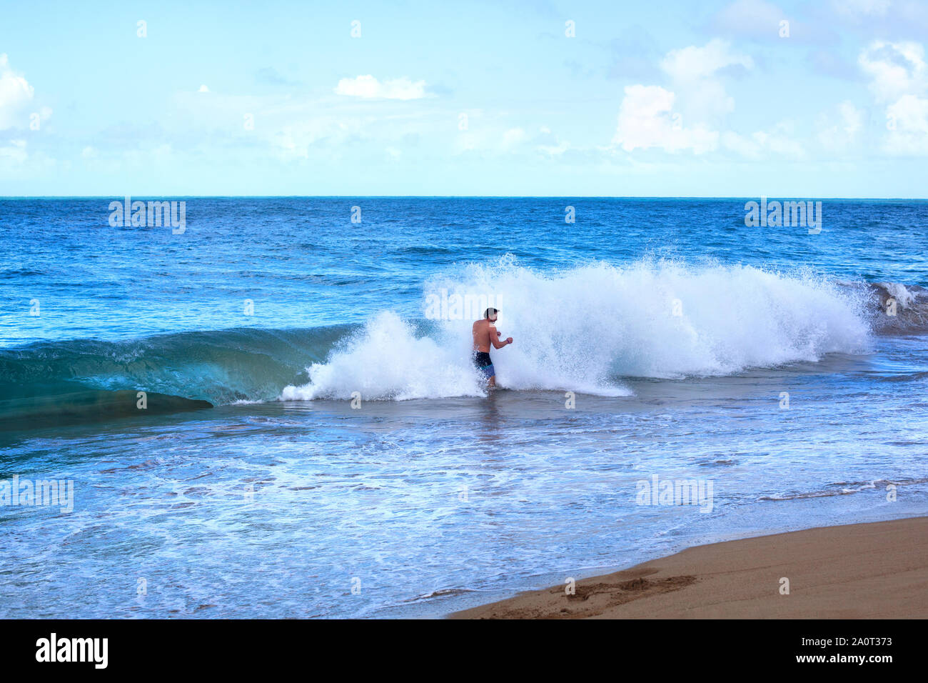 Sosua, Dominican Republic, December 26, 2016, man in the sea on the beach and big ocean wave with foam and splashes of water on the coast Stock Photo