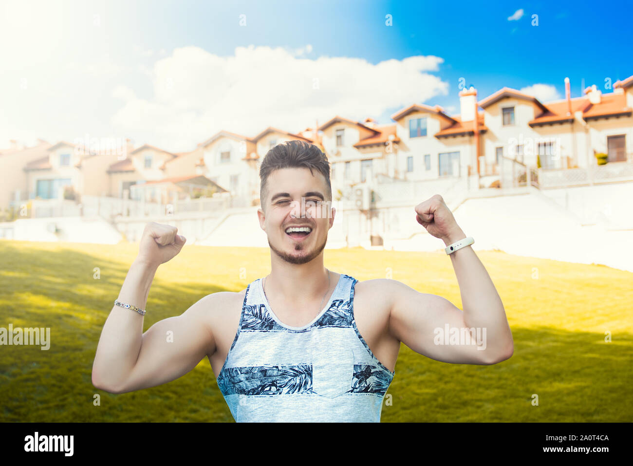 Expressive emotion. Attractive vacation. Happy young man got good news. beautiful cottages in the background. Stock Photo