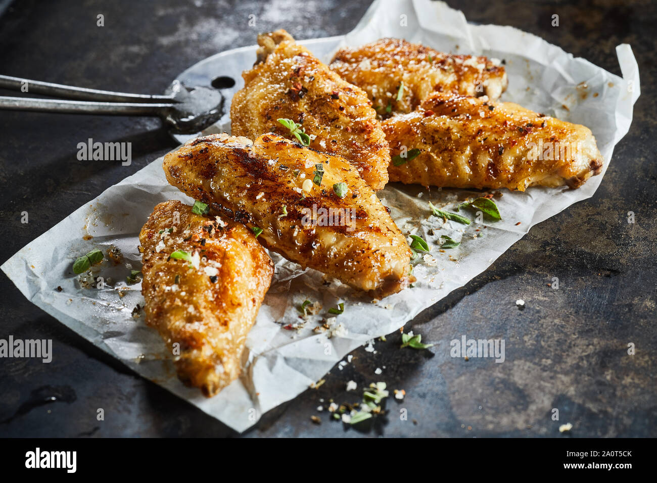 Tasty crispy spicy barbecued chicken wings or Buffalo wings garnished with  fresh chopped herbs and salt on crumpled paper in a close up view for a men  Stock Photo - Alamy