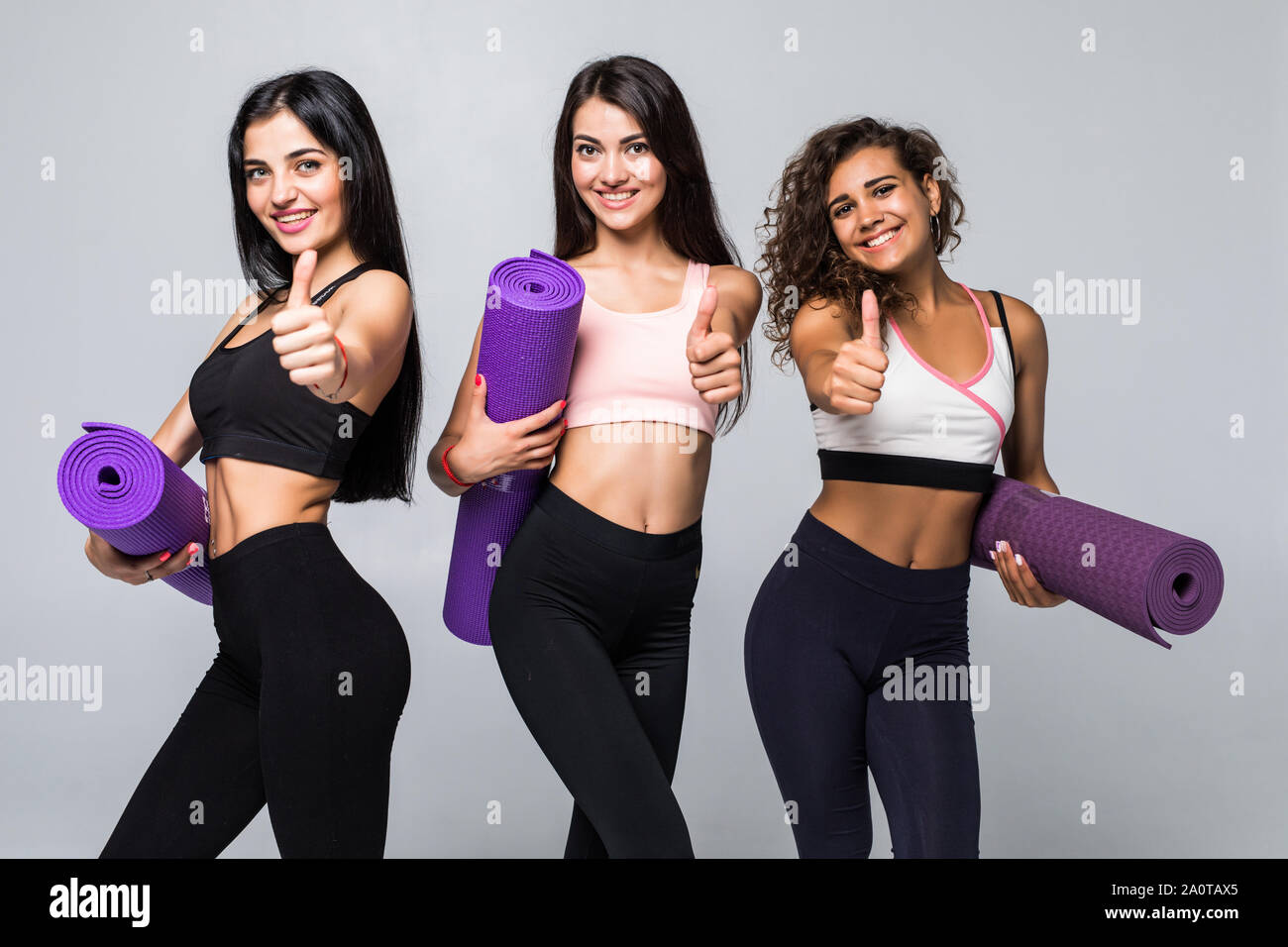 Three young fitness girls holding yoga mat while standing in gym Stock  Photo - Alamy