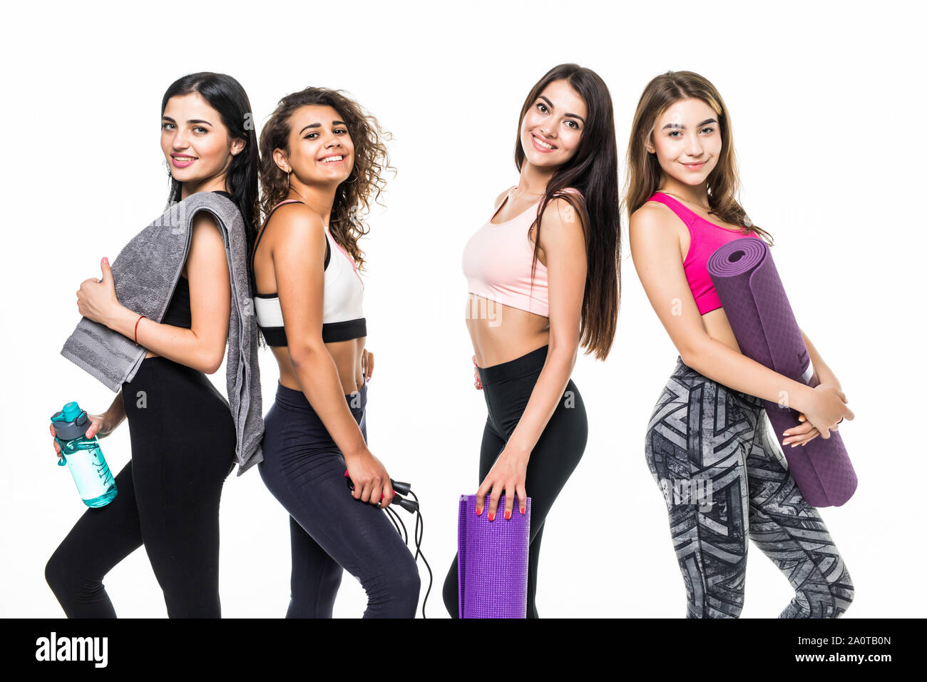 Four fitness girls in sportwear holding exercises equipment on white ...