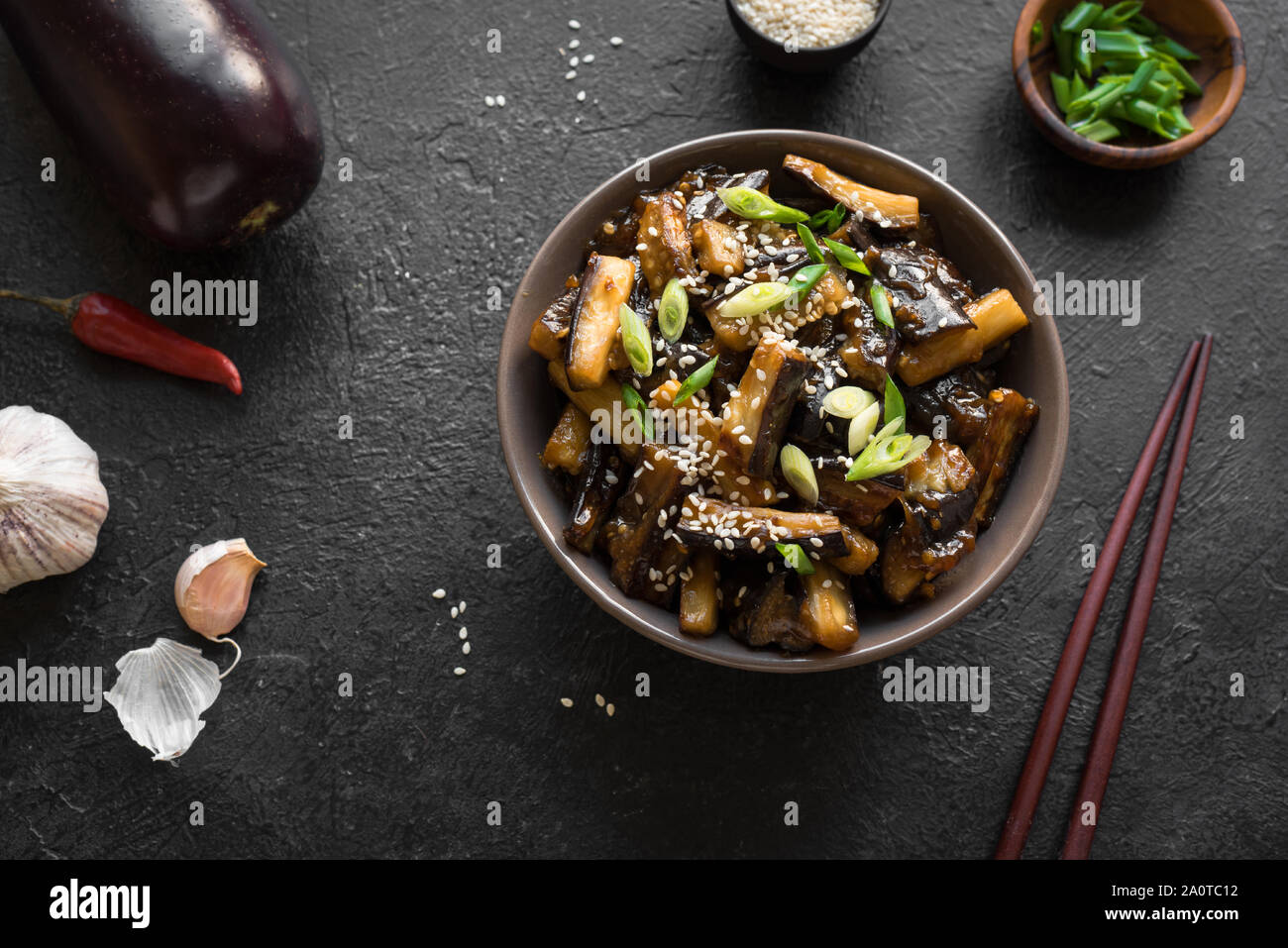 Stir fried aubergine in bowl. Corean, chinese or asian vegan meal - eggplant stir fry with soy sauce sweet glaze, top view, copy space. Stock Photo