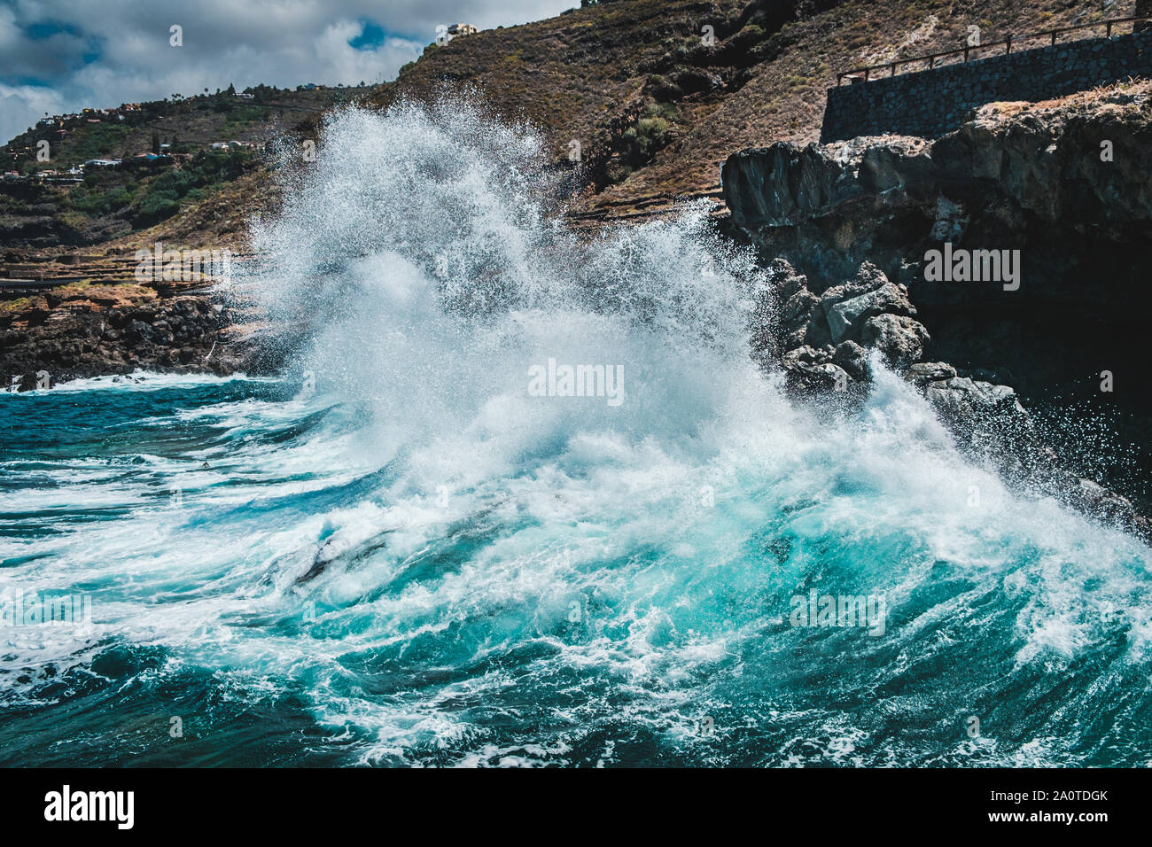 big wave crushing on rocky coast - waves hit rocks on shore - Stock Photo