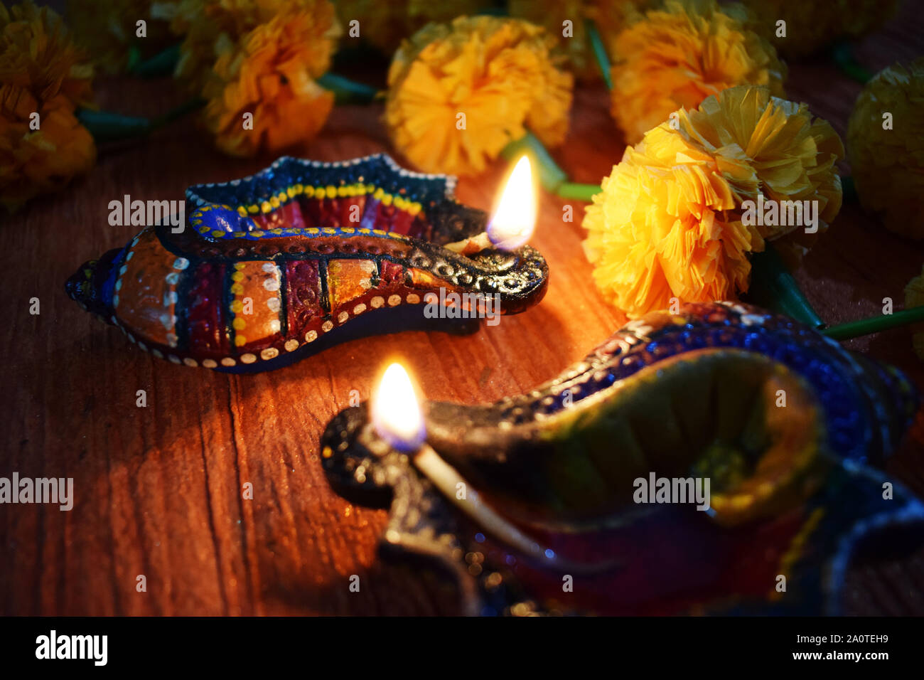Two conch shaped colorful designer diyas lit on occasion of Happy Diwali with marigold flowers on background Stock Photo