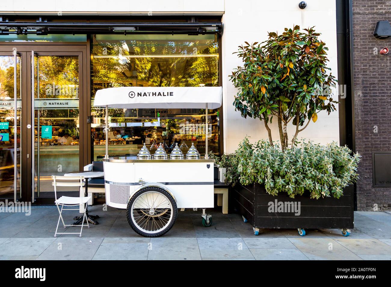 Ice cream trolley with silver pyramidal dome lids at Nathalie Cafe in Hanover Square, London, UK Stock Photo
