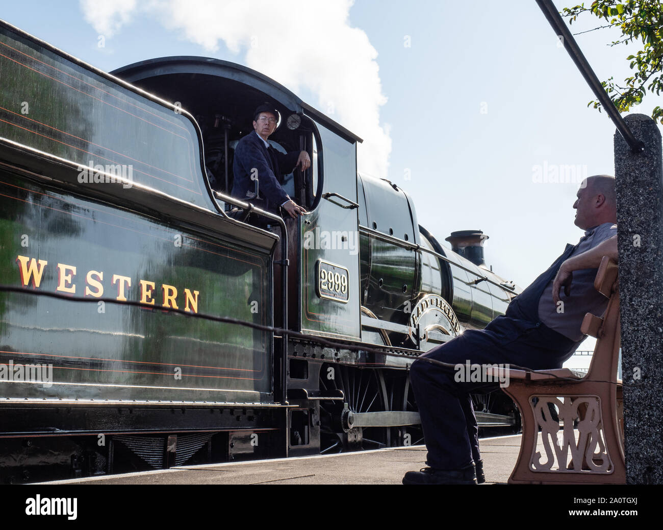 Driver in cab of steam train, fireman rests on bench Stock Photo