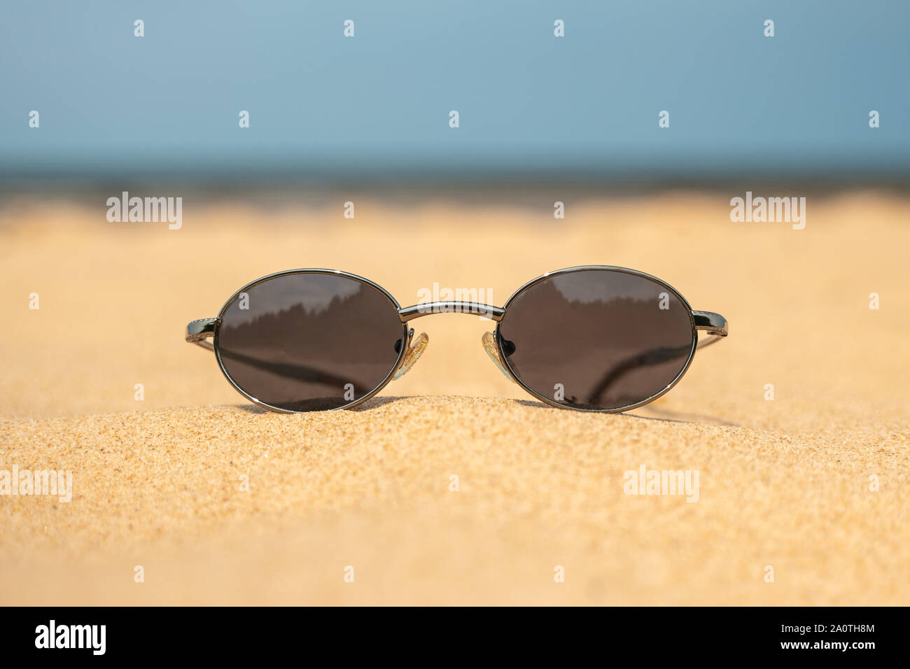 Sunglasses on beach sand with view to sea. The beach holiday is the ideal of vacations - what nearly every traveler whether young or old dreams of. Stock Photo