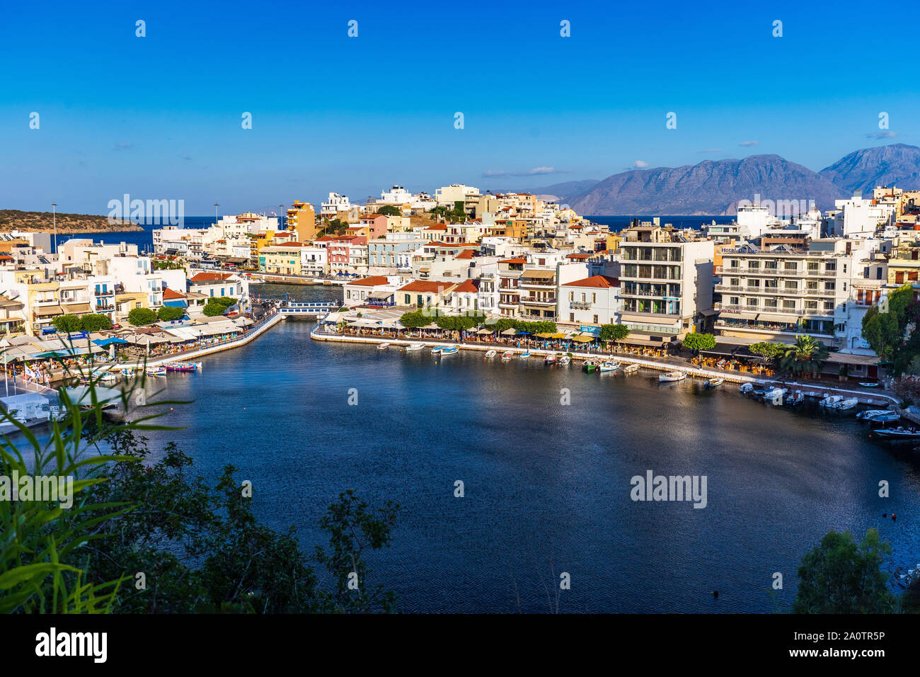 AGIOS NIKOLAOS, CRETE, GREECE: 12 September 2019: Lake Voulismeni and various colorful buildings in Agios Nikolaos seen at sunset, East Crete, Greece Stock Photo