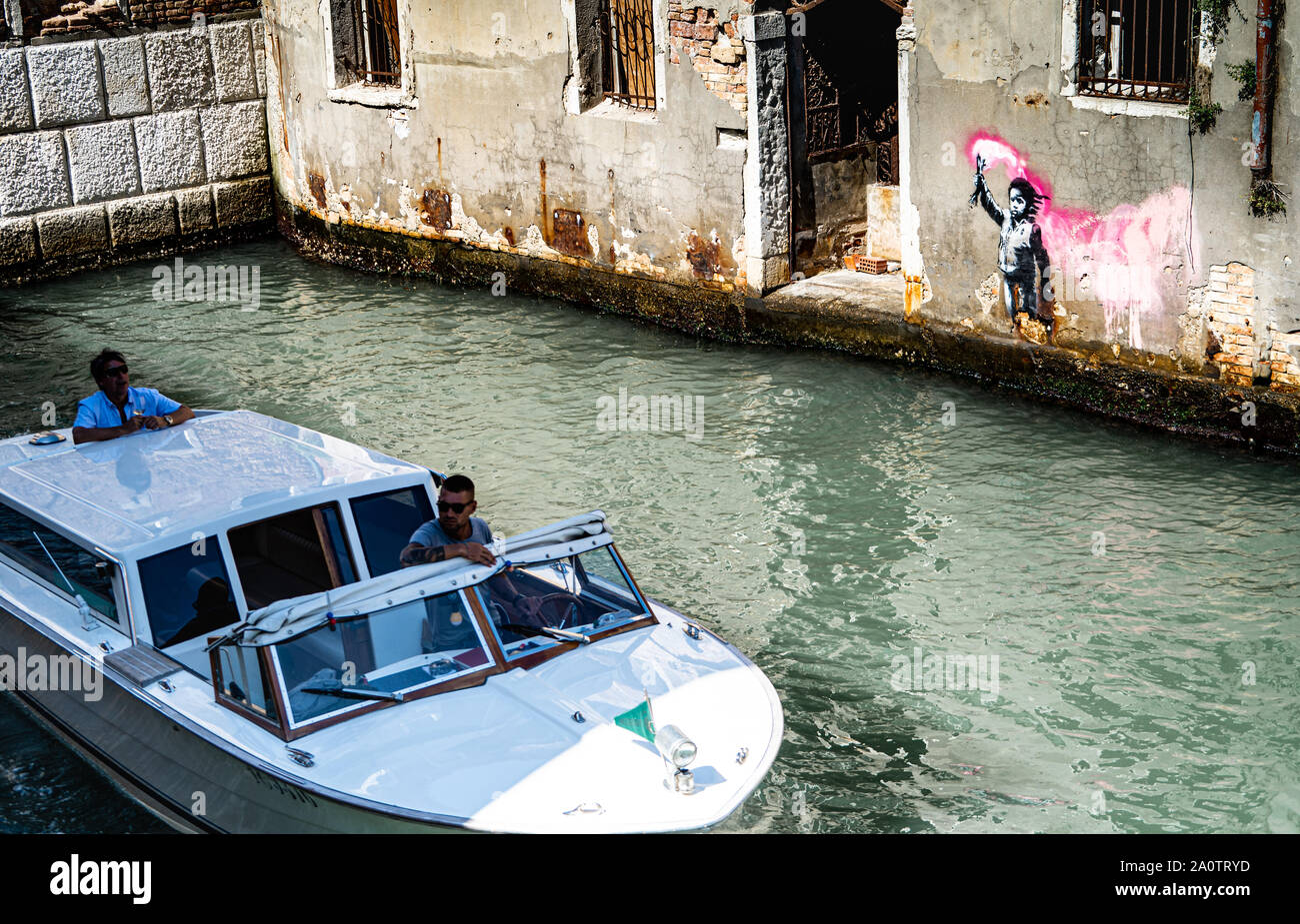 Banksy 'Migrant Child', mural / graffiti / art, Dorsoduro district, Venice, Italy with boat passing Stock Photo