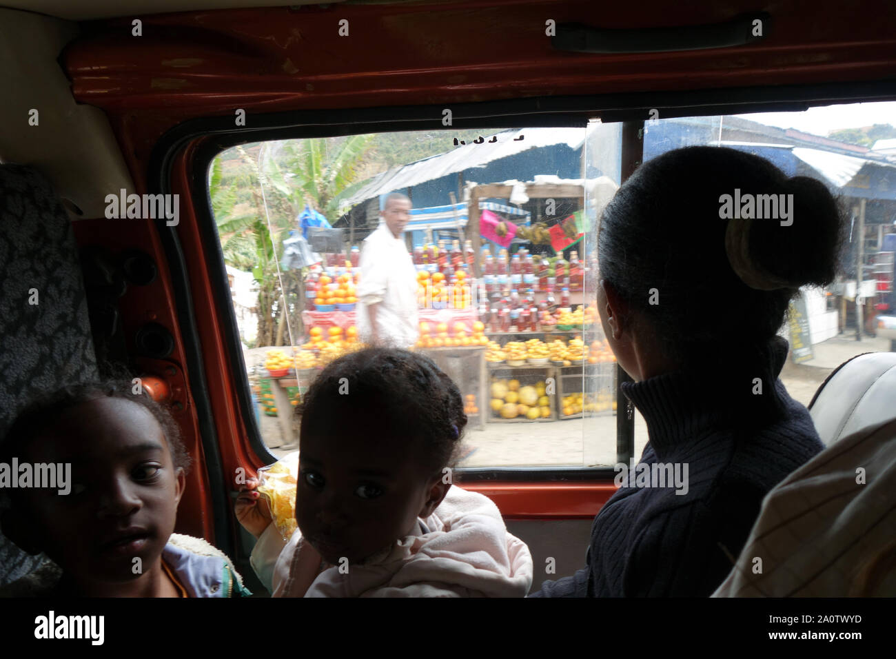 Little girls inside crowded taxi-brousse as colorful roadside stalls go by, Antananarivo, Madagascar. No MR or PR Stock Photo
