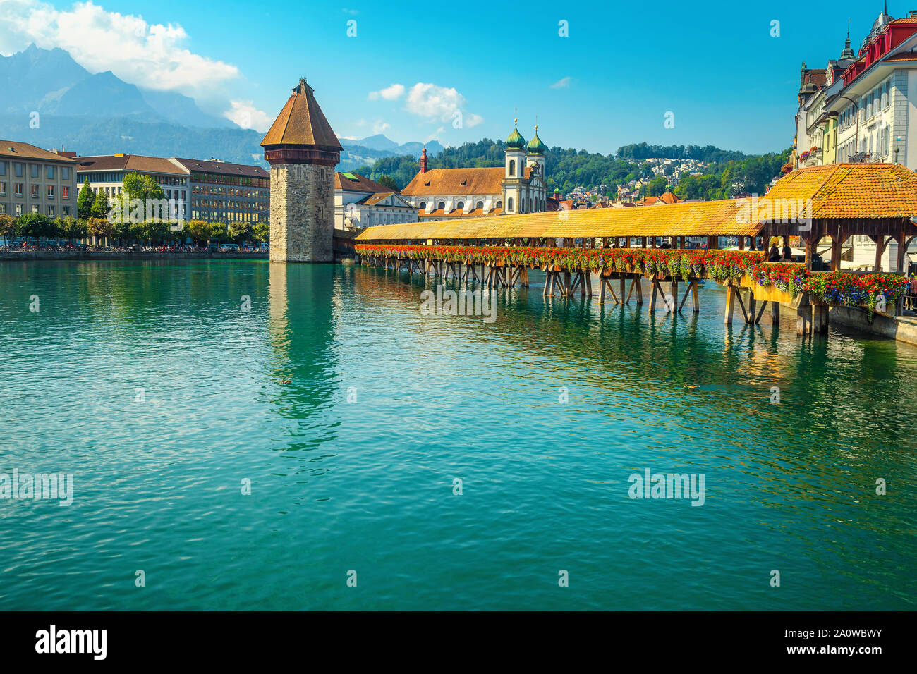 Spectacular touristic and travel destination in Lucerne. Famous Jesuitenkirche church with Reuss river. Fantastic cityscape view with flowered wooden Stock Photo