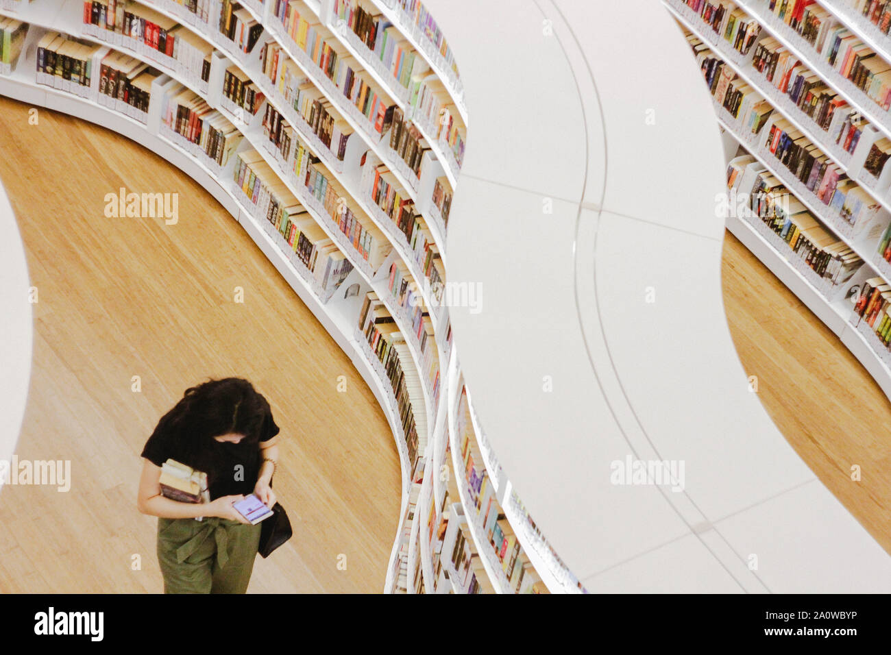 A book lover walks through bookshelves in the library in Singapore. It is said that ÒWhenever you read a good book, somewhere in the world a door open Stock Photo