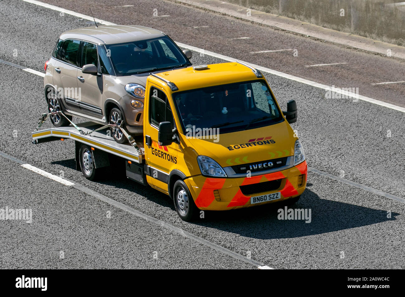 Egertons 24hr Vehicle roadside Recovery by yellow Iveco Daily 35S11 MWB; UK Vehicular traffic, transport, modern, saloon cars, south-bound on the 3 lane M6 motorway highway. Stock Photo