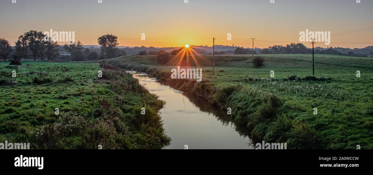 A sunrise over Trentham in Staffordshire. Pictured running through the landscape is a small stream called Longton Brook Stock Photo