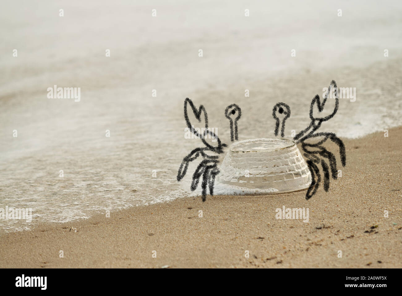 Funny doodle of crab made out of an image of plastic bowl being dumped on the beach, irony doodle of marine life being suffered from human plastic wat Stock Photo