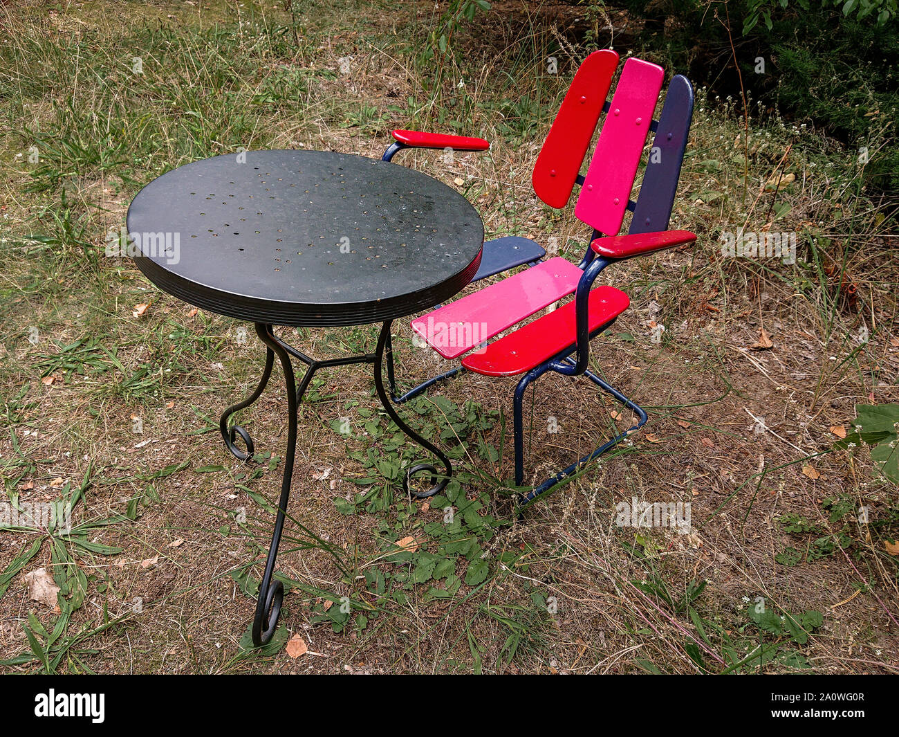 Colourful outdoor set of a red and purple painted old fashioned chair
