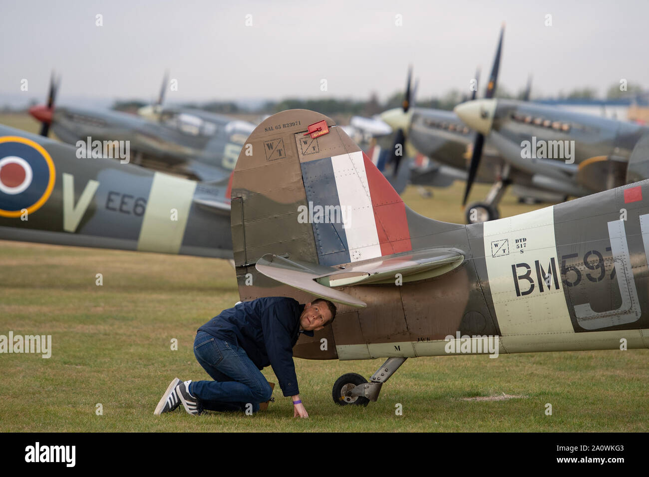 A flight mechanic inspects a Supermarine Spitfire during the Duxford Battle of Britain Air Show at the Imperial War Museum in Duxford, Cambridgeshire. Stock Photo