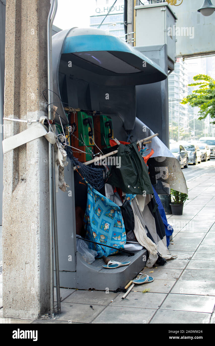Bangkok / Thailand - October 04 2018: Phone booth repurposed into a temporary shelter by a homeless man in Bangkok Thailand Stock Photo