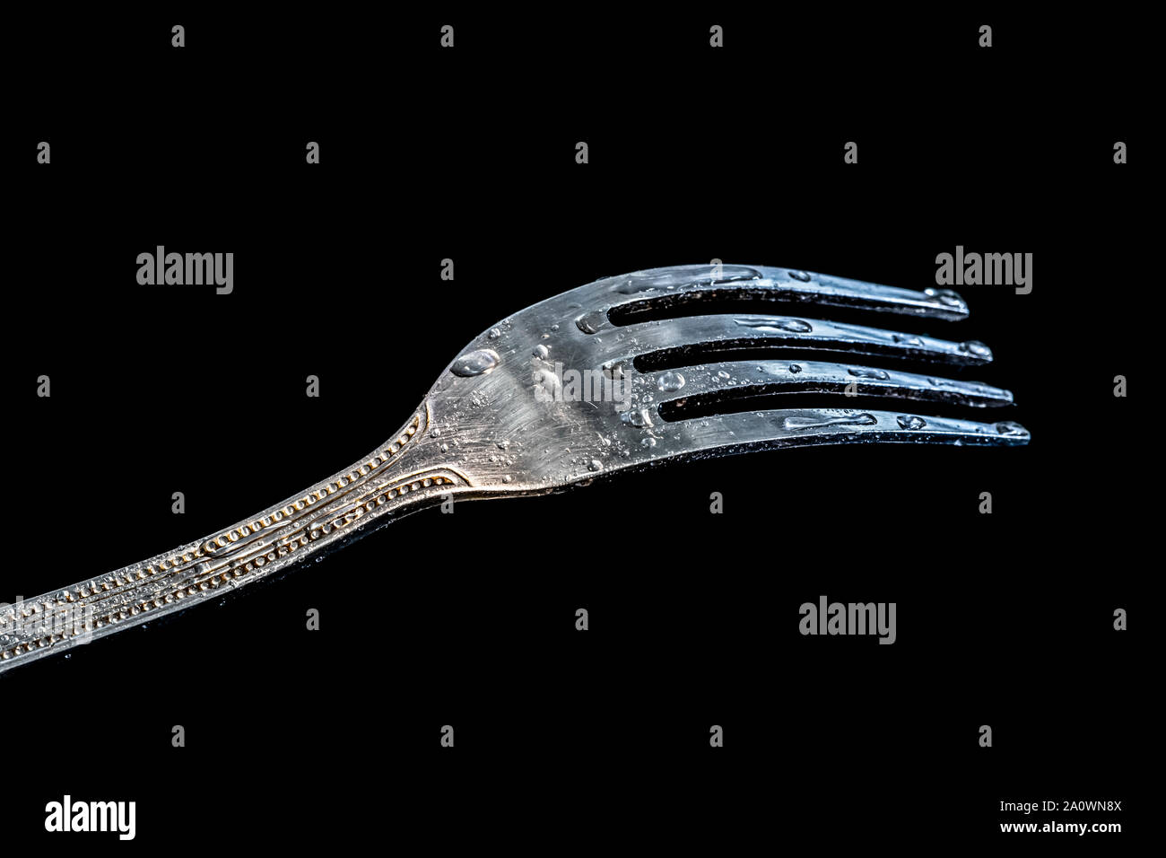 Single fork at the black table with water droplets on it. Stock Photo