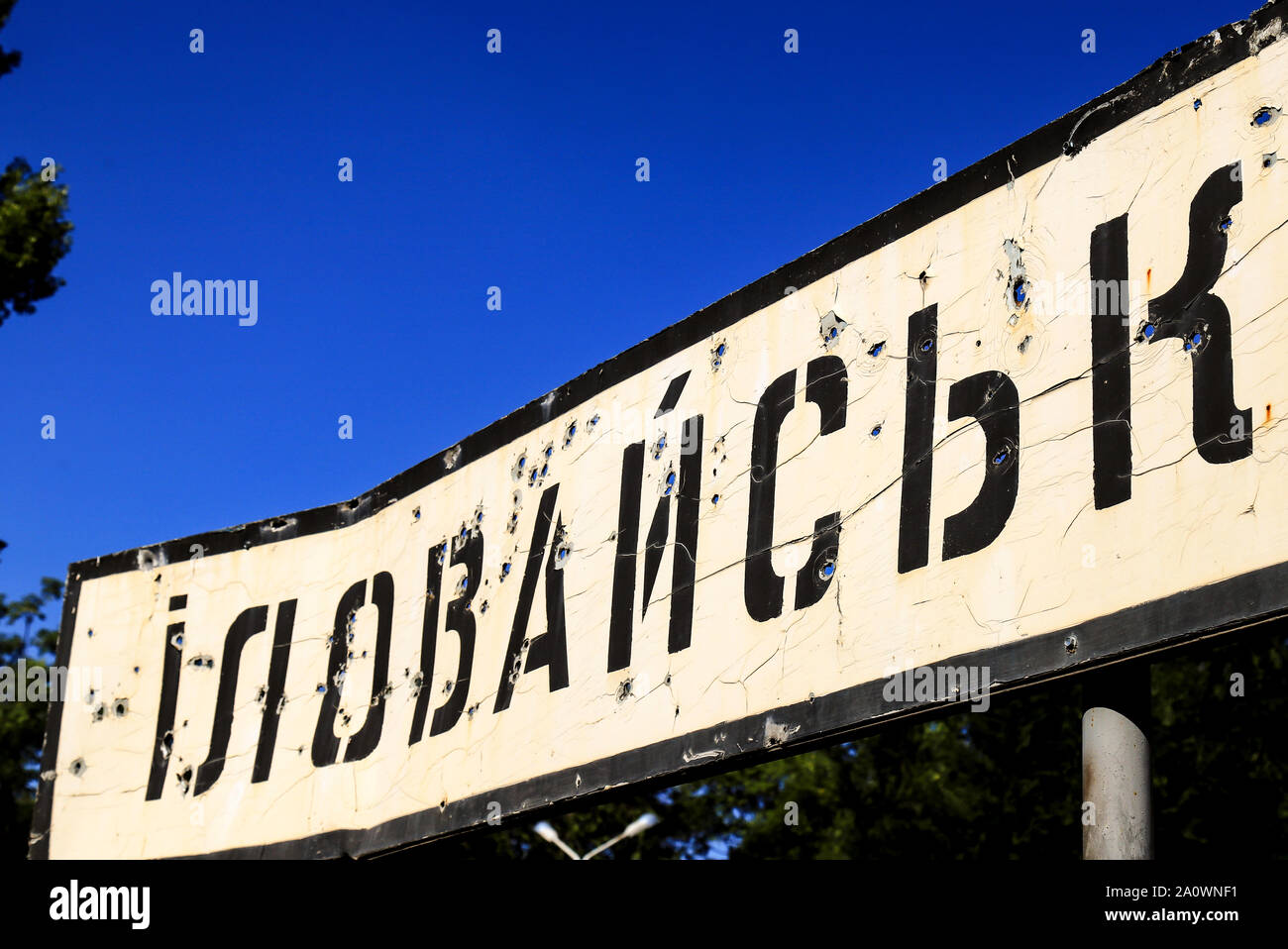 Road sign with the inscription in Ukrainian - Illowaysk, Donetsk region, broken by bullets during the war in the Donbass, Ukraine. Armed conflict Stock Photo