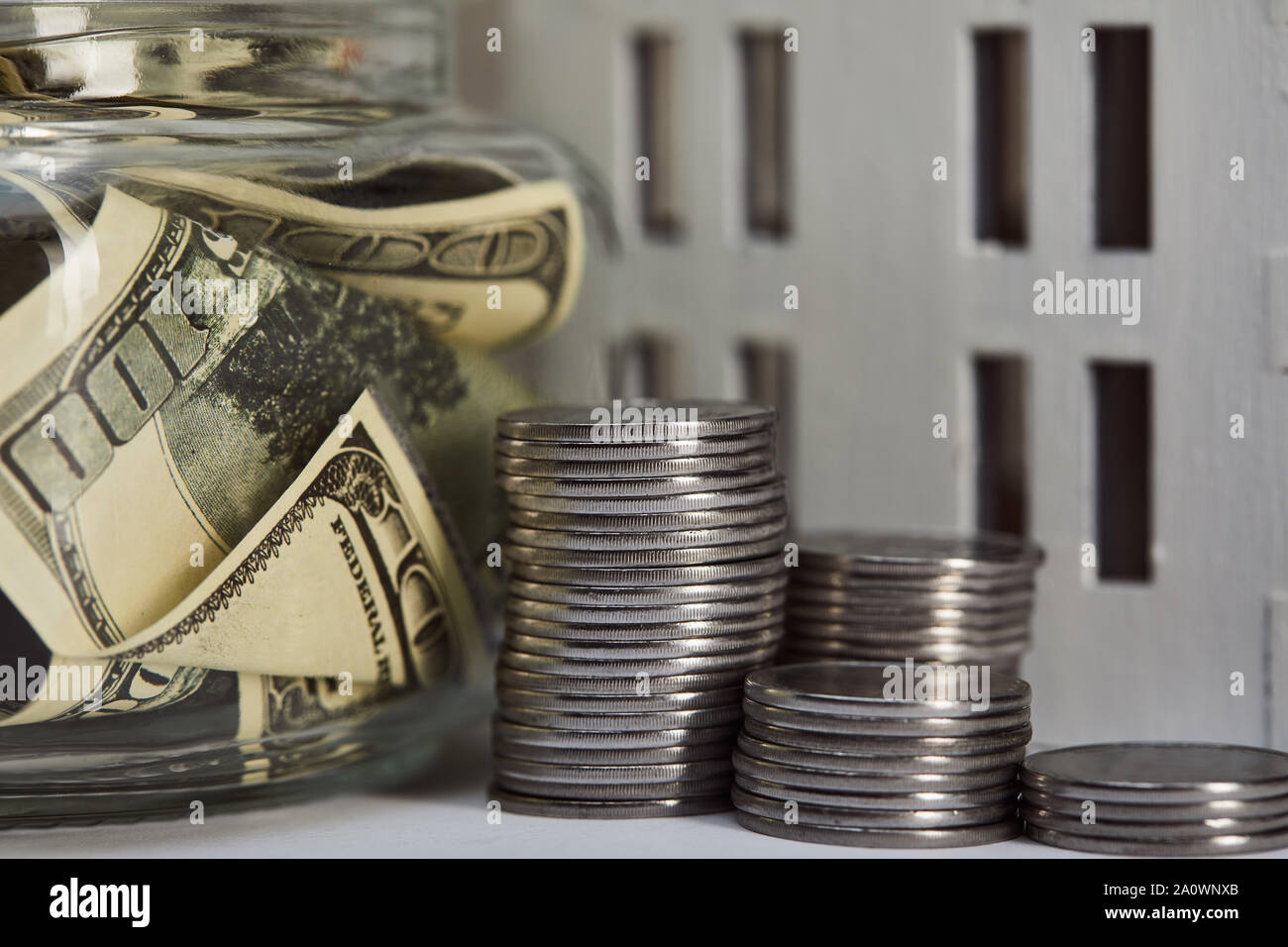 close up view of house model near silver coins and dollar banknotes in