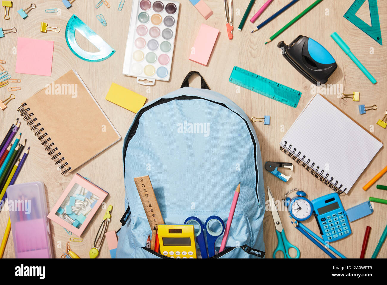 top view of various school supplies with blue backpack on wooden desk Stock Photo