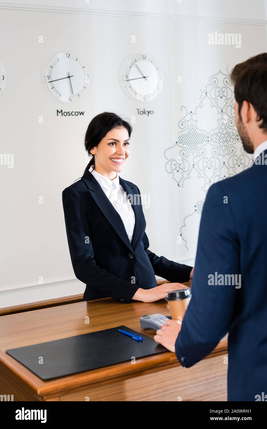 cropped view of man standing near happy receptionist in hotel Stock Photo