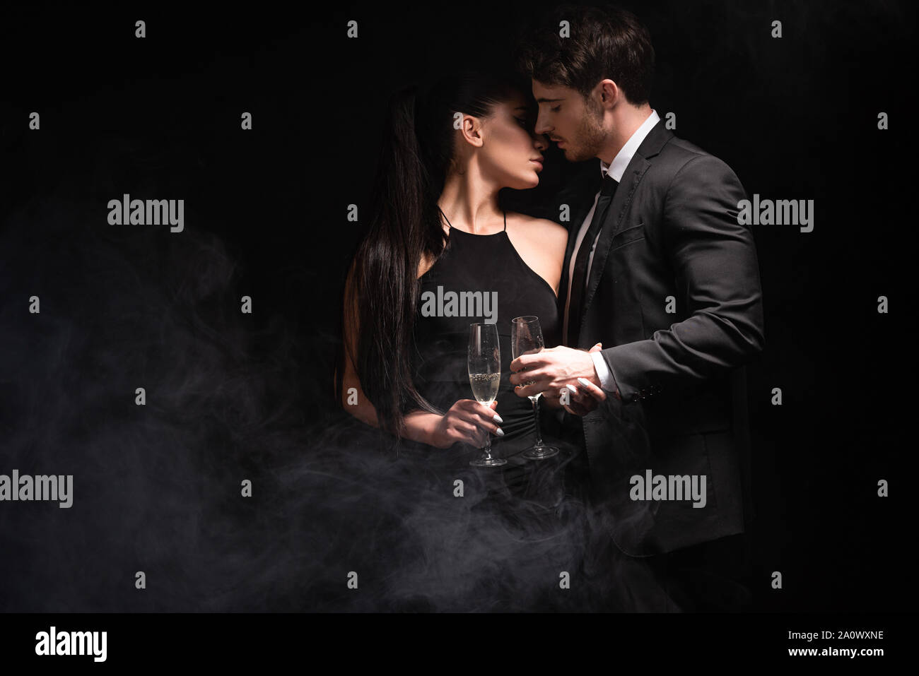 stylish couple with glasses on champagne kissing on black Stock Photo