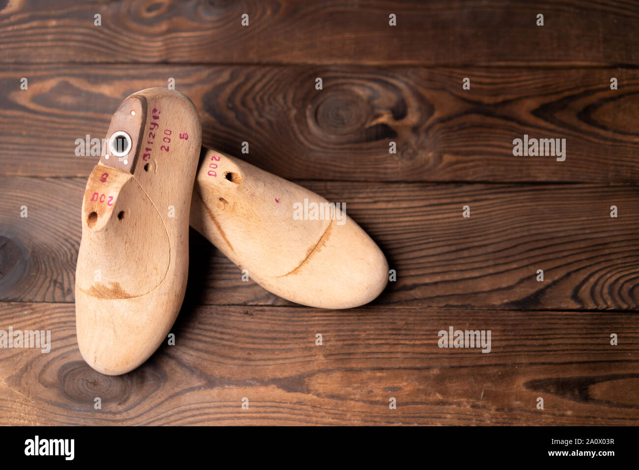 Leather samples for shoes and wooden shoe last on blue wooden table. Designer furniture clothes. Shoe maker workspace. Stock Photo