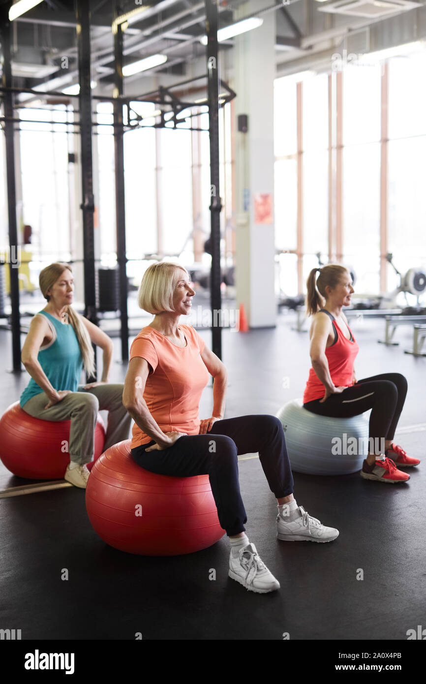 Full length portrait of three mature women working out in gym exercising with fitness balls, copy space Stock Photo
