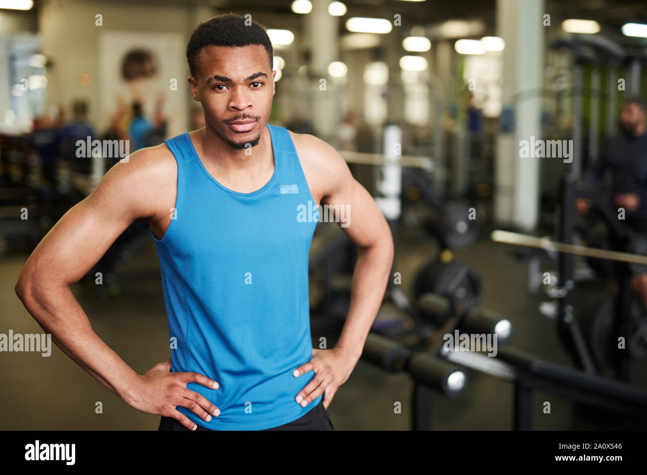 Waist up portrait of muscular fitness coach looking at camera while posing confidently in modern gym, copy space Stock Photo
