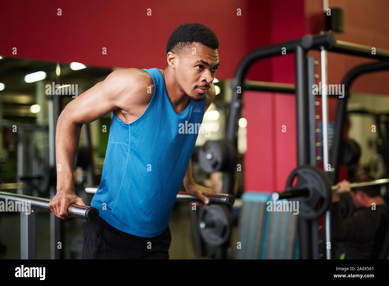 Portrait of handsome African-American man doing pull up exercises during workout in modern gym, copy space Stock Photo