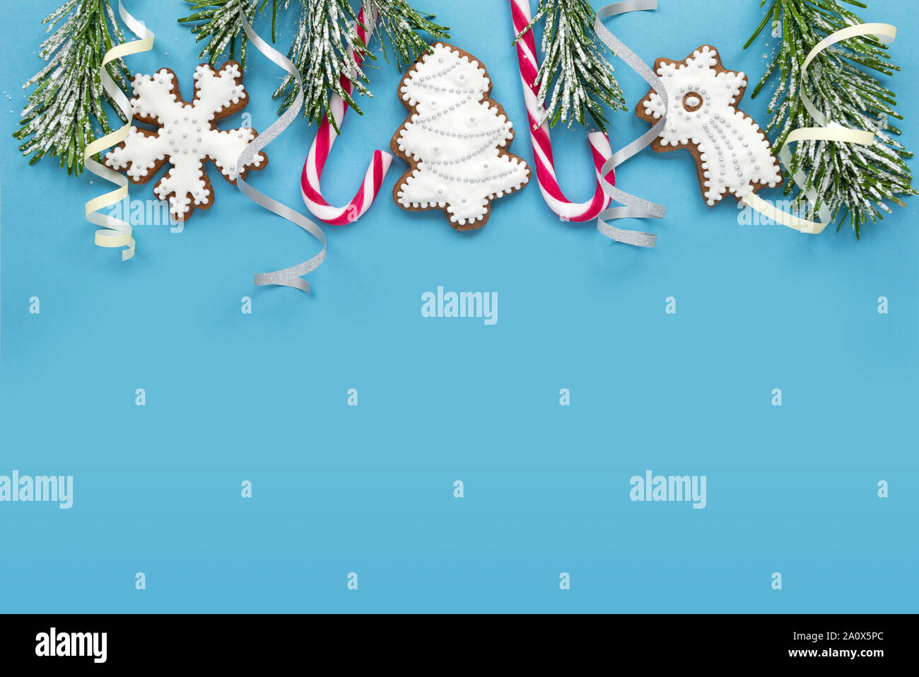 Frame with fir branches, cookies and Christmas decorations on a blue background. Top view. Stock Photo