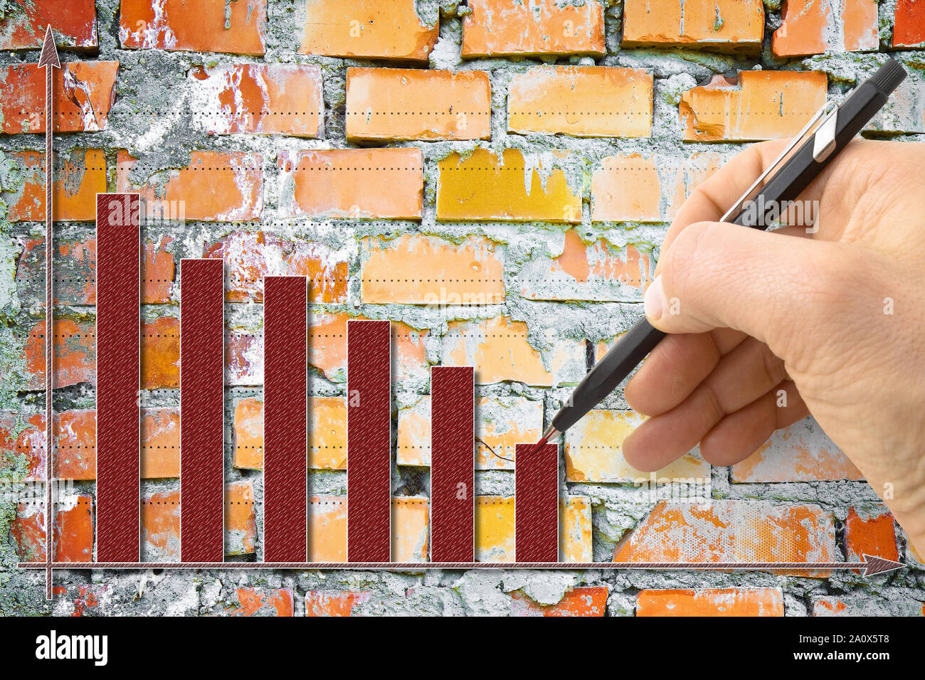 Hand draws a decreasing graph against a brick wall background - concept ...