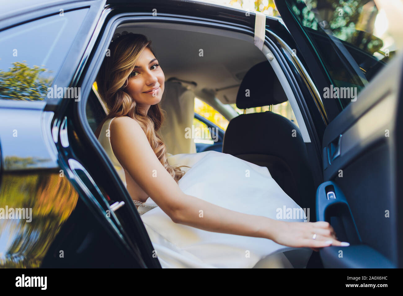 A bride takes pictures in the black car. Stock Photo