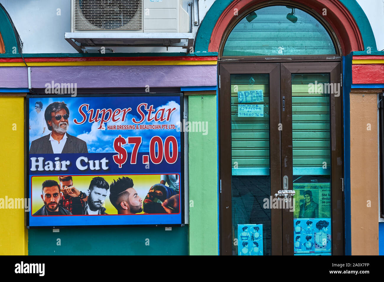 A barber shop in Little India, Singapore, advertising itself with a photo of Tamil movie star Rajnikanth; most customers are Tamil laborers from India Stock Photo