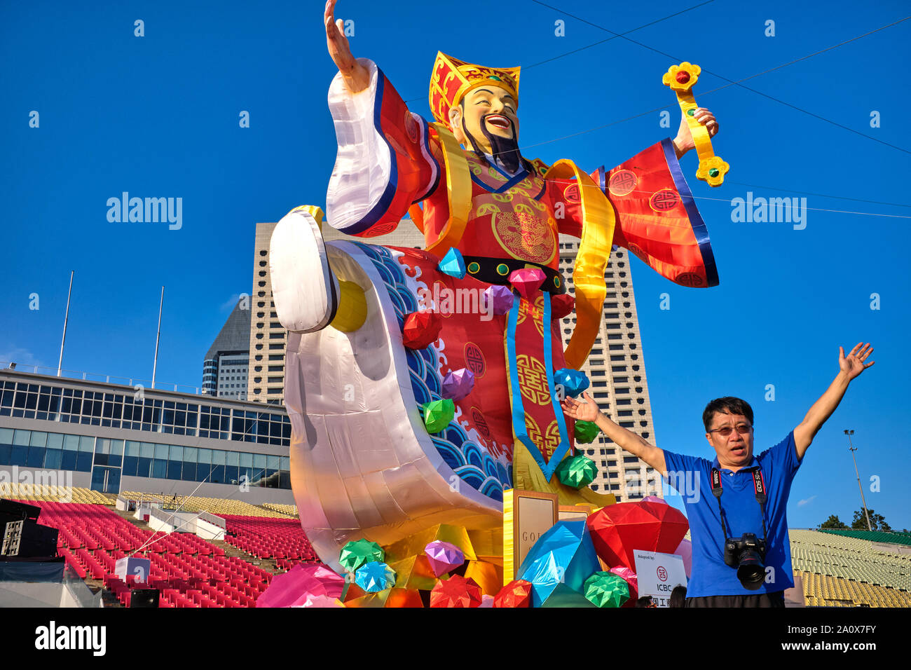 A Chinese tourist poses in front of a figure of the Chinese God of Good Fortune erected for Chinese New Year; at Esplanade, Marina Bay, Singapore Stock Photo