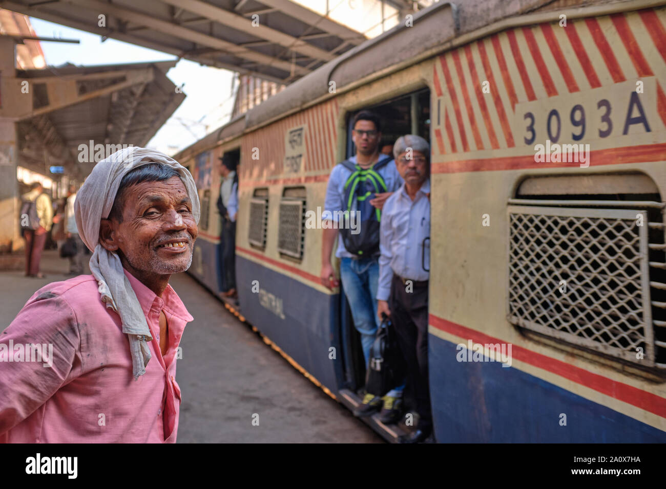 A happy porter at Chhatrapati Shivaji Maharaj Terminus (CSMT) in Mumbai, India, awaiting an incoming local train to forward his goods Stock Photo