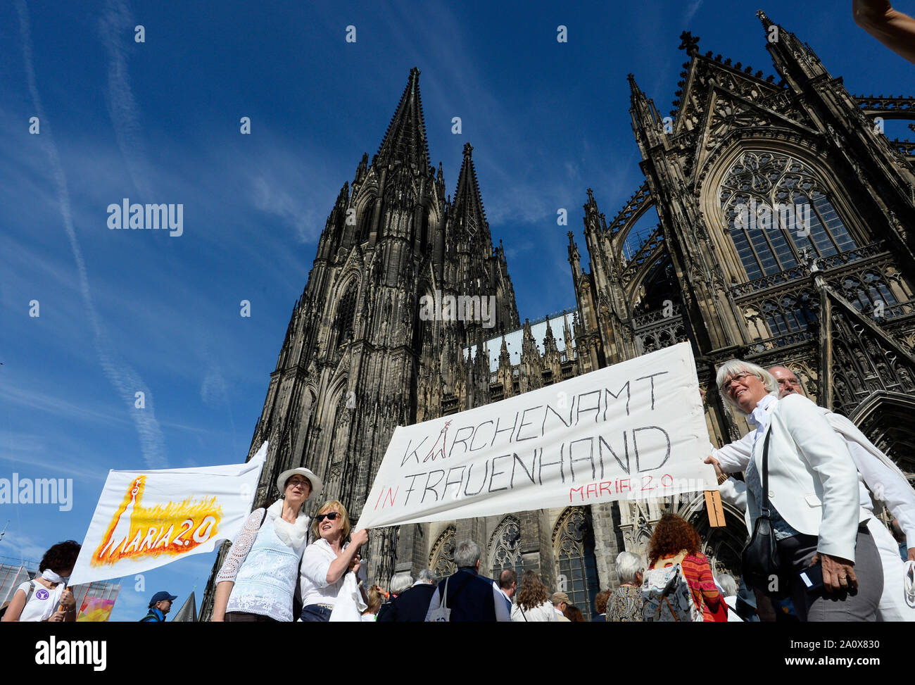 Cologne, Germany. 22nd Sep, 2019. Demonstrators of the 'Maria 2.0' movement stand in front of Cologne Cathedral with a banner with the inscription 'Kirchenamt in Frauenhand - Maria 2.0'. The movement 'Maria 2.0' demonstrated on Sunday with a human chain around the Cologne Cathedral for more equality in the Catholic Church. Credit: Roberto Pfeil/dpa/Alamy Live News Stock Photo