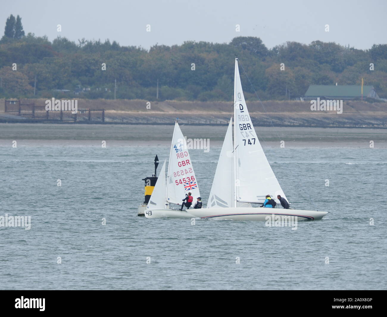 Queenborough, Kent, UK. 22nd September, 2019. 56th Medway Marathon - an annual 26 mile course on the tidal River Medway organised by Medway Yacht Club and open to both keelboats and sailing dinghies. The course starts at Upnor Rochester, and utilises various creeks on the Medway to make up the distance with the Queenborough Spit Buoy at the eastern extreme of the course. Pic: a 420 dinghy rounds the Queenborough Spit buoy ahead of a 3-person  Dragon keelboat. Credit: James Bell/Alamy Live News Stock Photo